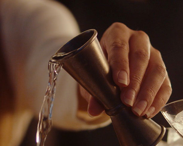 Hand pouring alcohol into glass.